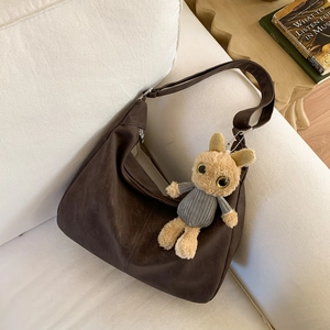 Vintage brown suede hobo tote bag with a cute rabbit plush pendant in a cozy home setting
