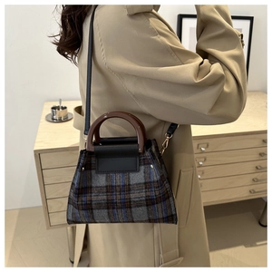 Detail of vintage plaid tweed handbag with leather strap on a model wearing trench coat