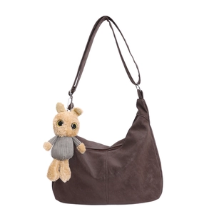 Brown matte hobo tote bag with adjustable strap and plush pendant on white background