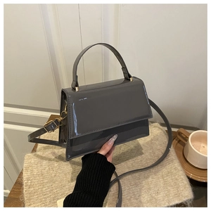 Detail of grey patent leather handbag with gold hardware and removable shoulder strap