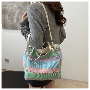 Vue détaillée d'un sac cabas tissé à rayures colorées avec des anses en cuir blanc