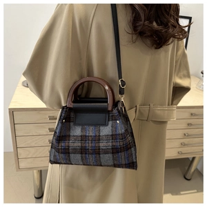 Detail of classic plaid wool handbag with brown resin handle and detachable shoulder strap