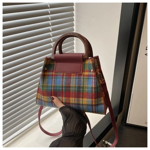 Detail of multi-color plaid tweed handbag featuring brown handle and red shoulder strap