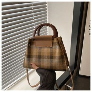 Detail of British style checkered tote bag with dark brown handles and leather strap