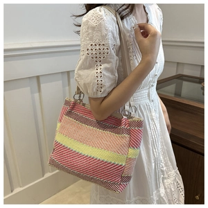 Détail d'un sac cabas tissé à rayures colorées avec bandoulière en cuir beige et anneau
