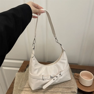 Glossy white half-moon underarm bag with decorative buckle and adjustable strap