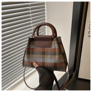Detail of checkered plaid handbag featuring retro resin round handle and leather trim