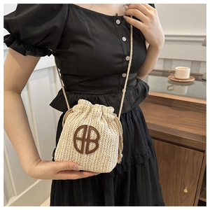 Détail du sac seau tissé avec cordon de serrage, logo HB en cuir et bandoulière tressée