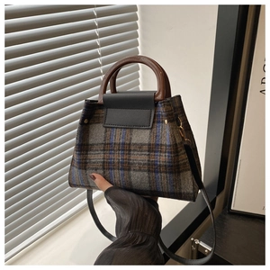 Detailed view of vintage plaid wool tote with wooden handle and black leather flap cover