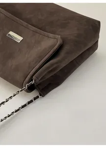 Detail of matte dark brown shoulder bag with silver metal lock and chain strap
