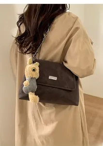 Detail of a dark brown large shoulder tote with silver buckle and plush bunny charm