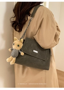 Detail of dark grey-green crossbody bag with silver chain strap and plush animal charm