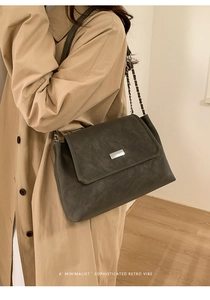 Detail of dark grey retro crossbody bag with matte leather texture and silver chain
