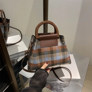 Retro plaid tweed handbag with brown leather flap and stylish round handles in a studio setting
