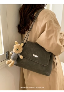 Detail of dark grey frosted shoulder bag with chain strap and plush rabbit charm