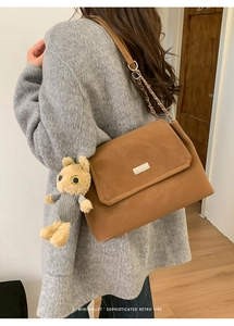 Brown leather shoulder bag with chain strap and a cute plush rabbit pendant detail