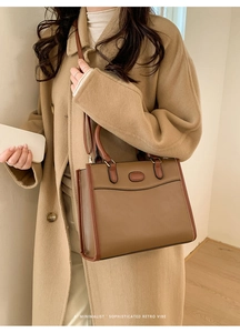 Detail van een minimalistische bruine patchwork handtas gedragen met wollen jas