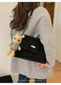 Detail of black velvet shoulder bag with silver chain and cute plush rabbit charm
