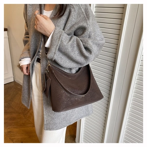 Détail du sac cabas en daim avec surpiqûres contrastées et mini pendentif assorti
