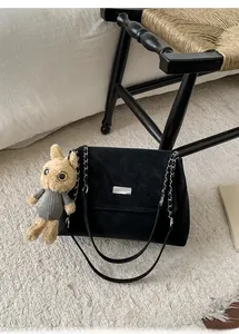 Detail of black matte flap bag with silver buckle and cute plush rabbit charm accessory