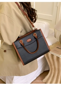 Detail van retro kleurblok tote tas in zwart en bruin leer met gouden hardware