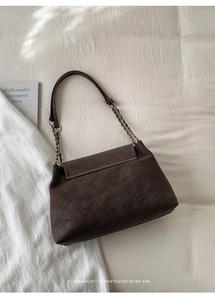 Detail of vintage dark brown faux suede shoulder bag with gold chain strap design