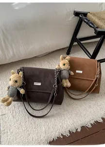 Close-up of vintage flap tote bags with metal buckles and plush rabbit pendant detail