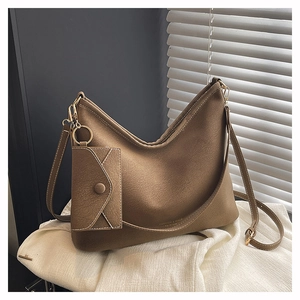 Détail du sac cabas marron avec pochette, texture cuir mat et fermoirs dorés brillants