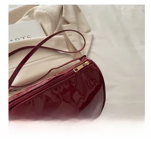 Détail du sac Boston en cuir verni bordeaux avec fermeture éclair dorée et bandoulière fine