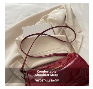 Détail du sac à bandoulière en cuir verni rouge avec lettrage FASHION doré et sangle