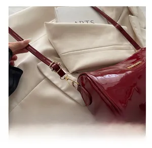 Gros plan sur la boucle en métal doré et le fermoir mousqueton du sac en cuir verni rouge