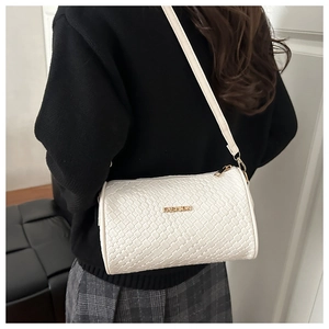 Détail d'un sac cylindrique blanc à texture tressée avec lettrage doré de mode chic