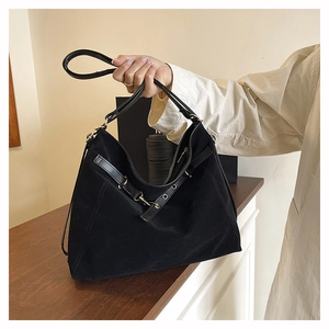 Macro view of black suede tote bag detail with leather straps and metallic eyelets