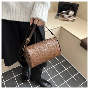Détail du sac Boston marron foncé tressé avec lettrage FASHION doré sur un mannequin