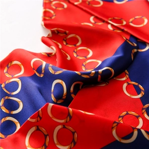 Close-up of silk scarf with red and blue color blocking and golden ring pattern