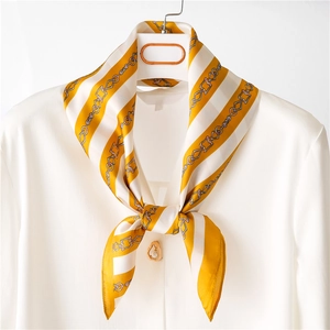 Élégant foulard en soie jaune avec imprimé chaîne noué sur un col de chemise blanc