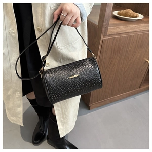 Détail du sac cylindre noir avec texture tressée et logo fashion en métal doré