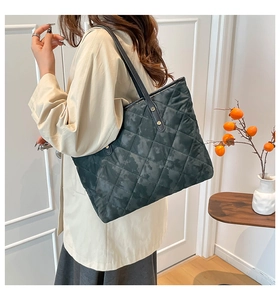 Détail du sac cabas matelassé foncé avec coutures en losange et rivets dorés