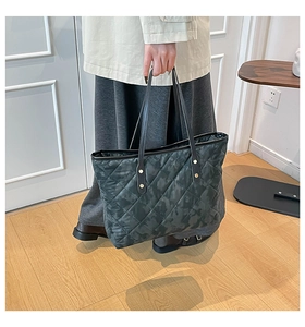 Gros plan du sac fourre-tout matelassé vert foncé avec motifs losanges et rivets dorés