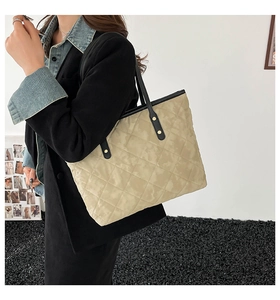 Détail du cabas matelassé beige avec poignées en cuir noir et rivets métalliques dorés