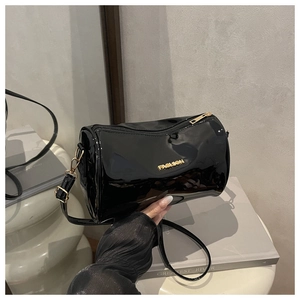 Détail d'un sac cylindrique en cuir verni noir avec inscription 'FASHION' dorée et fermeture éclair