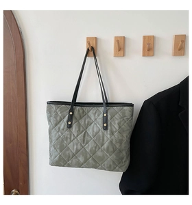 Détail du sac cabas gris matelassé avec des anses en cuir et un motif de losanges