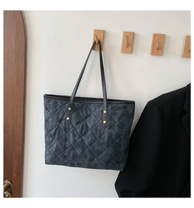 Détail d'un sac cabas matelassé avec motif camouflage et rivets en métal doré