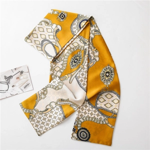 Détail d'un foulard en soie jaune avec motifs de chaînes dorées et bords à franges