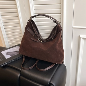Large dark brown suede tote bag convertible to backpack on a black leather bench