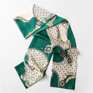 Détail d'un foulard en soie verte avec motifs de chaînes dorées et texture satinée