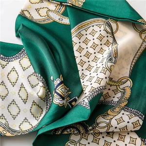 Détail d'un foulard en soie avec tissu vert émeraude et motifs de chaînes dorées