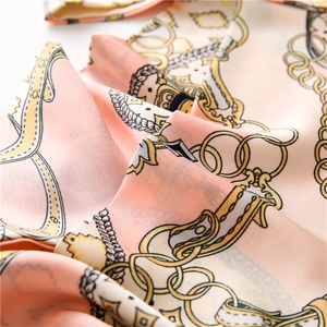 Gros plan d'un foulard en soie aux motifs de chaînes dorées et boucles rétro