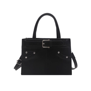 Minimalist black handbag with silver rivets and decorative straps in a structured design