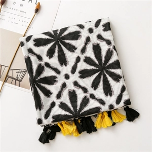 Detailed macro view of black floral print scarf with yellow and black tassels
